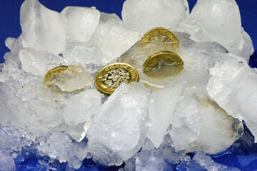 Pound coins frozen in ice. Frozen assets concept.