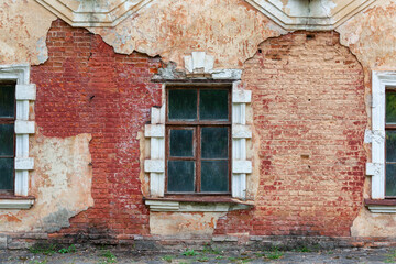 Front view of old damaged brick wall with windows.