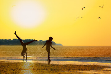 Silhouettes of children on the beach at sunset