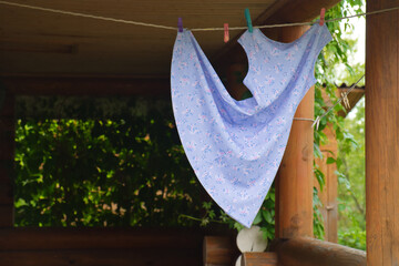 The child dress dries on a clothesline after wash in the garden at the summertime