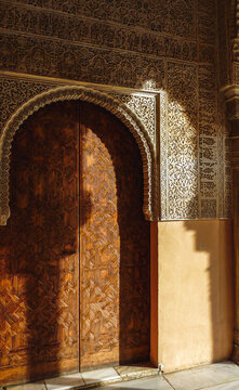 Afternoon sun casts shadows on an ornate door and archway at El Alhambra, in Granada, Spain.