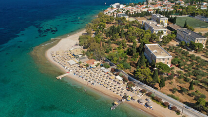 Aerial drone photo of organised with sun beds emerald beach of Kaikia in Ligoneri area near old town of Spetses island, Saronic gulf, Greece