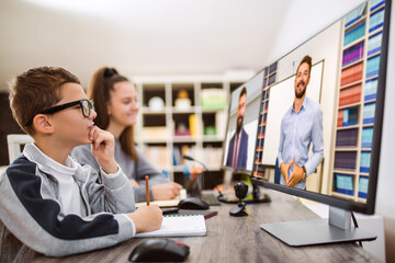 Boy and girl studies at home and doing school homework. Distance learning online education.