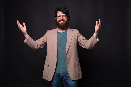 Photo of cheerful bearded man in casual making welcome gesture