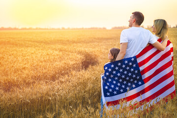 Back view of a unrecognizable Happy family in wheat field with USA, american flag on back.