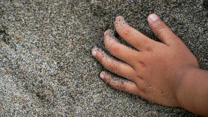 children's hands holding beach sand