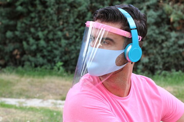 Young man wearing face shield and protective mask 
