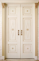 large white doors with forged handles, entrance to an expensive apartment, vertical photo, place for text, woodwork, patterned doors, baroque style, beautiful entrance