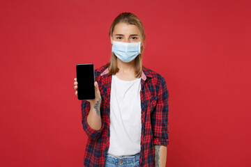 Young blonde girl in checkered shirt sterile face mask isolated on red background. Epidemic...