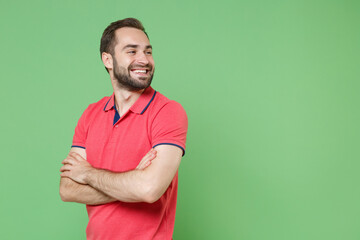 Smiling young bearded man guy in casual red pink t-shirt posing isolated on green wall background...