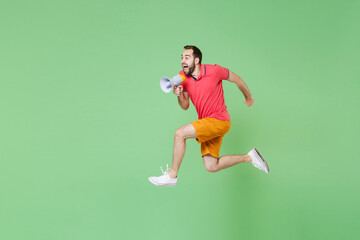 full length Crazy young man guy in casual red pink t-shirt posing isolated on green background...