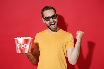Screaming young bearded man guy in casual yellow t-shirt 3d glasses isolated on red background....