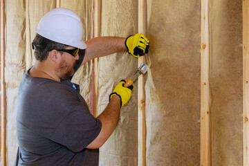 Man installing thermal insulation layer under the wall using mineral wool