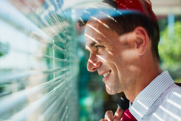 Businessman looking out window blinds