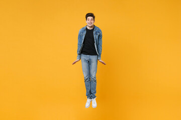 Fototapeta na wymiar full length Smiling young man guy 20s in casual denim clothes posing isolated on yellow wall background studio portrait. People sincere emotions lifestyle concept. Mock up copy space. Jump having fun