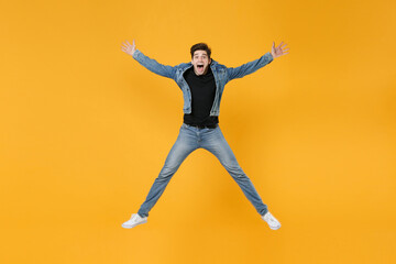 Fototapeta na wymiar full length Shocked young man guy in casual denim clothes posing isolated on yellow background studio portrait. People sincere emotions lifestyle concept. Mock up copy space. Jump spreading hands legs