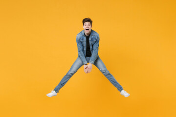 Fototapeta na wymiar full length Shocked young man guy in casual denim clothes posing isolated on yellow background studio portrait. People emotions lifestyle concept. Mock up copy space. Jump like dancing spreading legs.