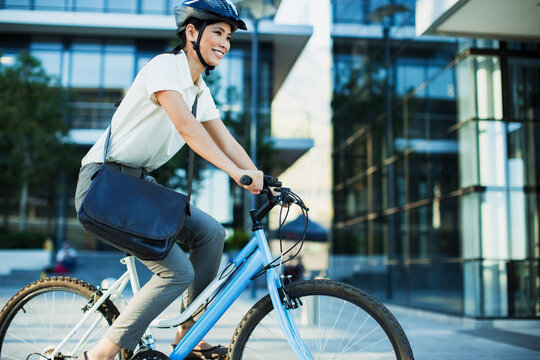 Businesswoman bike riding outside urban building