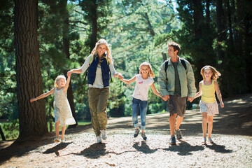 Smiling family holding hands and walking in woods