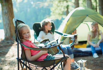 Smiling girl sitting in chair at campsite