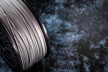 A coil of filament for 3d printing. Bright thermoplastic of grey color. Reel vertical view.