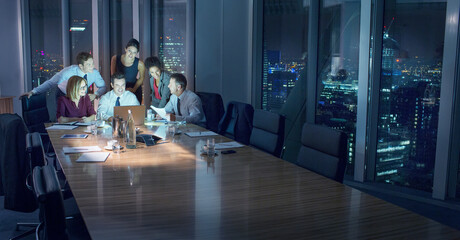 Business people working at laptop in conference room at night