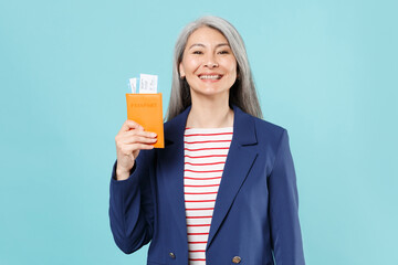 Smiling gray-haired business woman in blue suit posing isolated on blue background studio portrait....