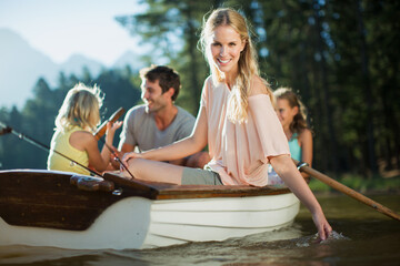 Obraz premium Smiling woman with family in rowboat on lake