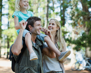 Father carrying daughter on shoulders in woods