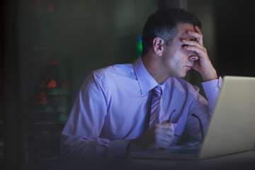 Tired businessman working late at laptop