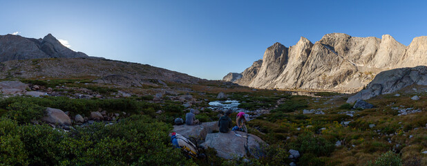 A panoramic shot of three backpackers pausing for a break while hiking the Wind River High Route....