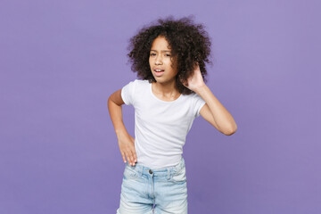 Curious little african american kid girl 12-13 years old in white t-shirt isolated on violet...