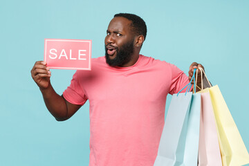 Amazed young african american man guy in casual pink t-shirt isolated on blue background studio...