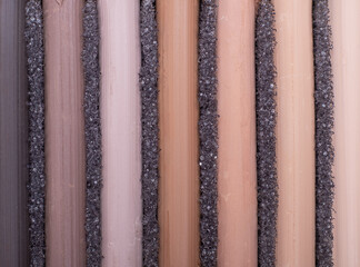 New crayons of pastels of brown scale and different shades are neatly arranged in a row in a box. Vertical layout. Close-up. Crayons are in dark gray foam. From light brown to dark brown.