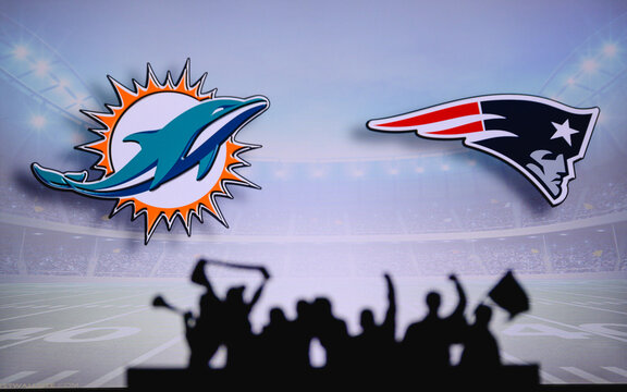 Miami Dolphins Vs. New England Patriots. Fans Support On NFL Game. Silhouette Of Supporters, Big Screen With Two Rivals In Background.