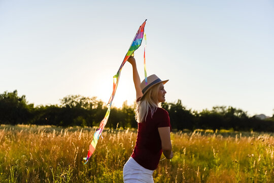 Portrait of a young and carefree woman launching kite on the greenfield. Concept of active lifestyle in nature