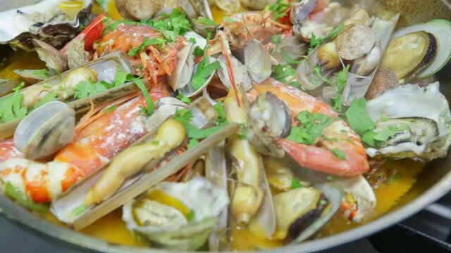 Cooking a cataplan, a Portuguese dish, with organic, clean seafood on fire. Horizontal video. Close-up.