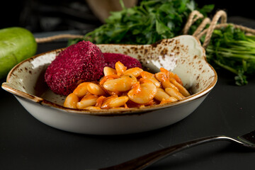 Boiled beans and beetroot patties in a plate, on a wooden table