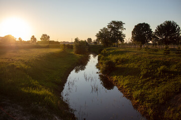 landscape, a small river at dusk with the golden colors from the sun