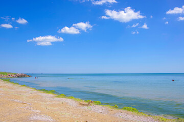 A deserted sea coast with blue water and a sky with clouds.
