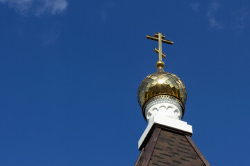 
Golden dome with a cross on the roof of the church against the blue sky