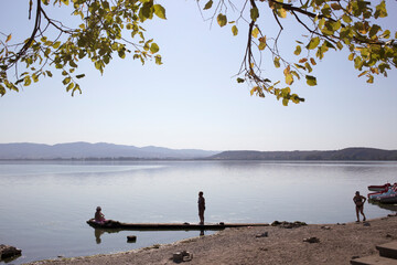 Silhouettes of older women enjoy the benefits of Dojran Lake with the Greek mountains in the background.