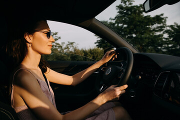 Young woman driving on a highway at the sunset. Driving school concept.