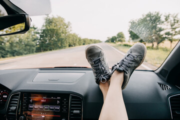 Female feet on a car dashboard by the windshield. Road trip concept.