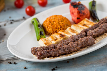shish meatball kebab from turkish cuisine. served with white plate on wooden table.