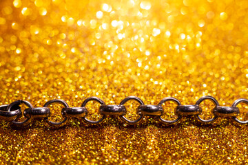 
Copper color chain on a gold shiny background with bokeh