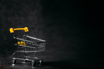 Small supermarket grocery push cart for shopping toys with wheels isolated on a dark background....
