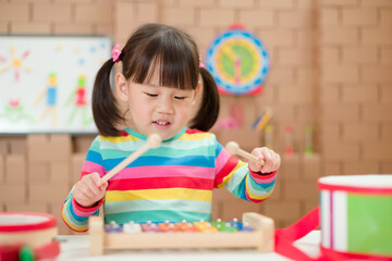 toddler girl play xylophone at home for homeschooling