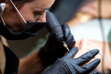The girl artist paints an eyebrow tattoo. The process of tattooing. Permanent makeup	