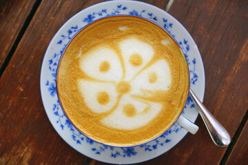 Cup of warm cappuccino coffee with a flower foam design on top